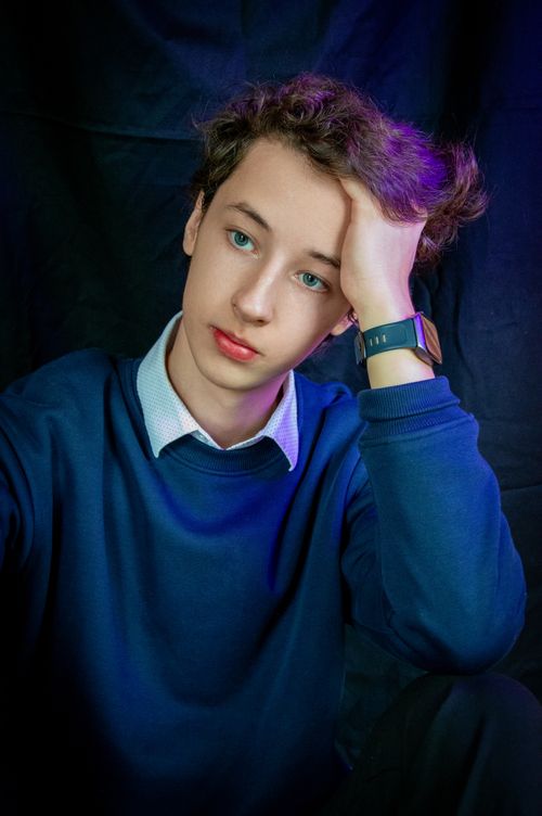Free Close-up portrait of a teenage boy in deep thought, wearing a blue sweater. Stock Photo