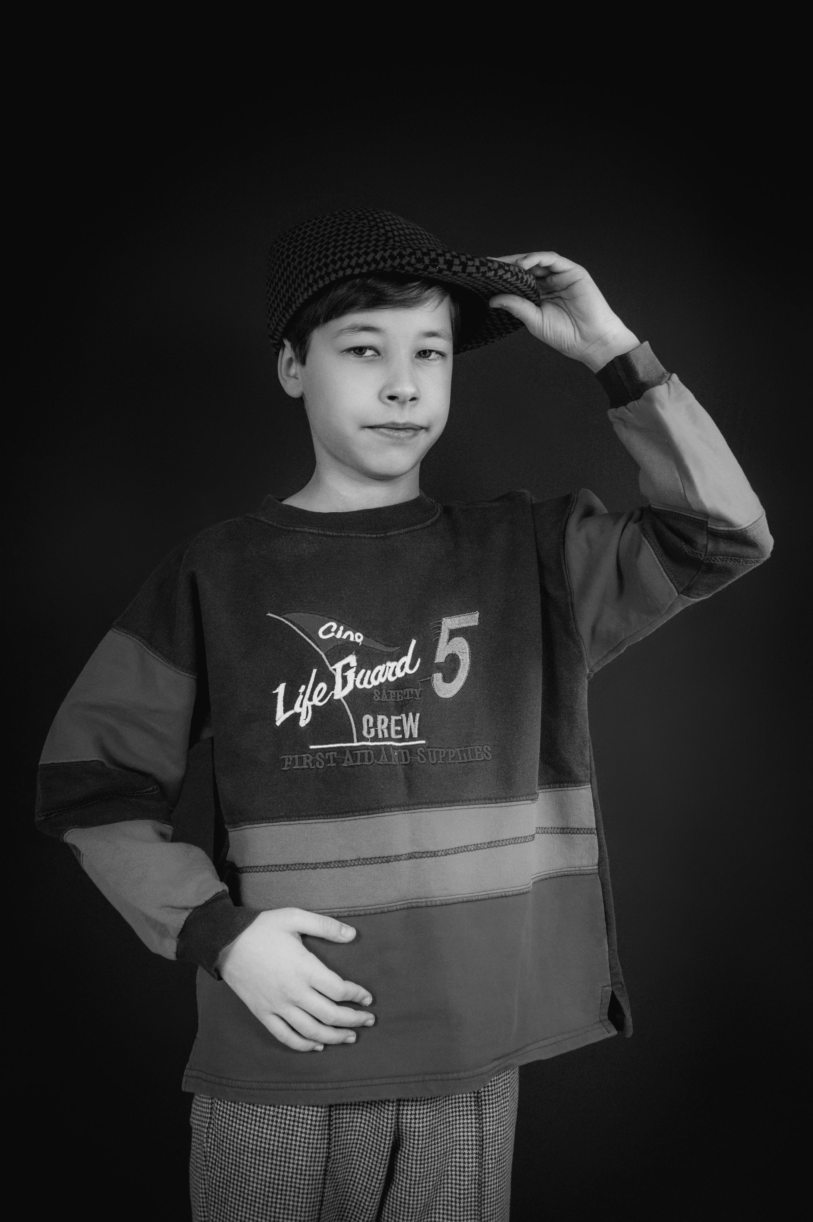 Kostnadsfria Svartvitt porträtt av en pojke som poserar med en keps som utstrålar vintagevibbar. Stock foto