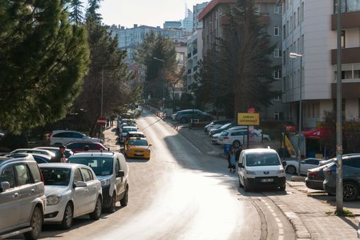 A quiet residential street in Ankara, Türkiye with parked cars and trees on a sunny day.