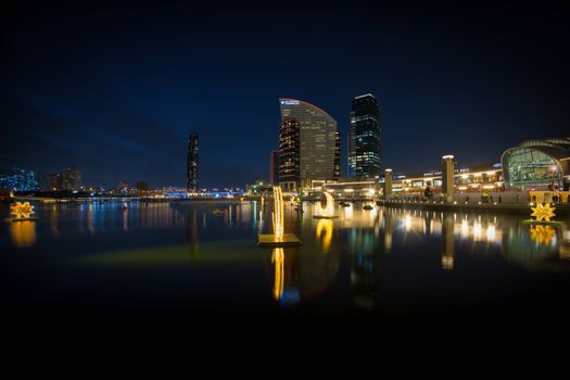 Stunning night city skyline with illuminated buildings reflecting on the water.