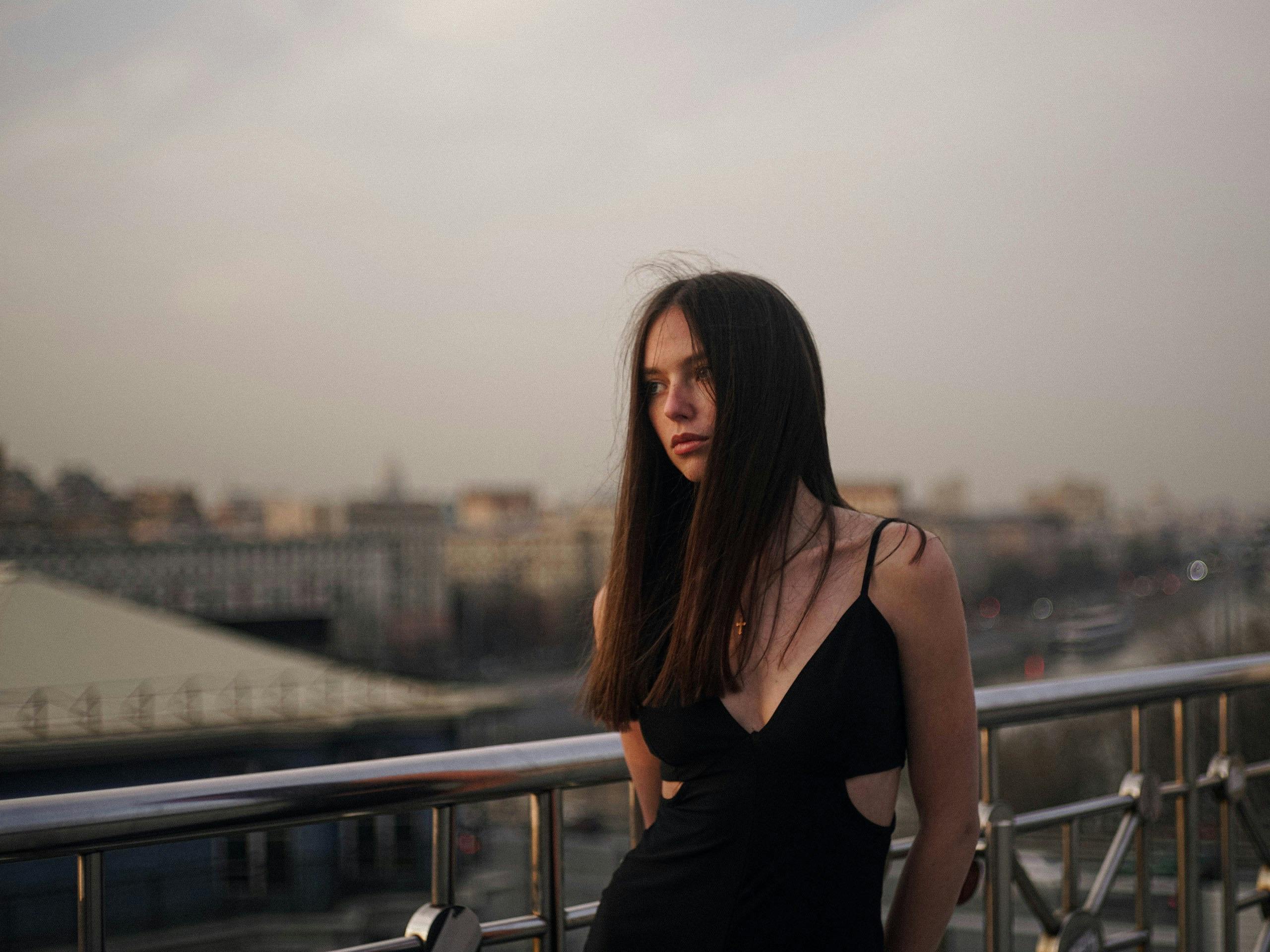 бесплатная Элегантная женщина в черном платье на балконе в Москве, Россия, на закате. Стоковое фото