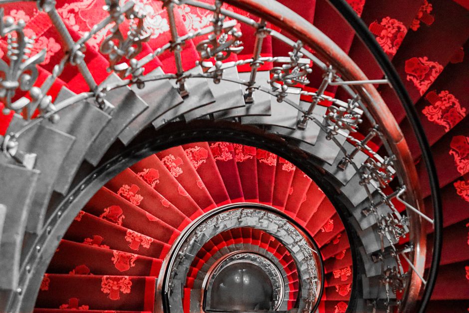 Dramatic aerial view of an ornate red spiral staircase in Tokyo, Japan.