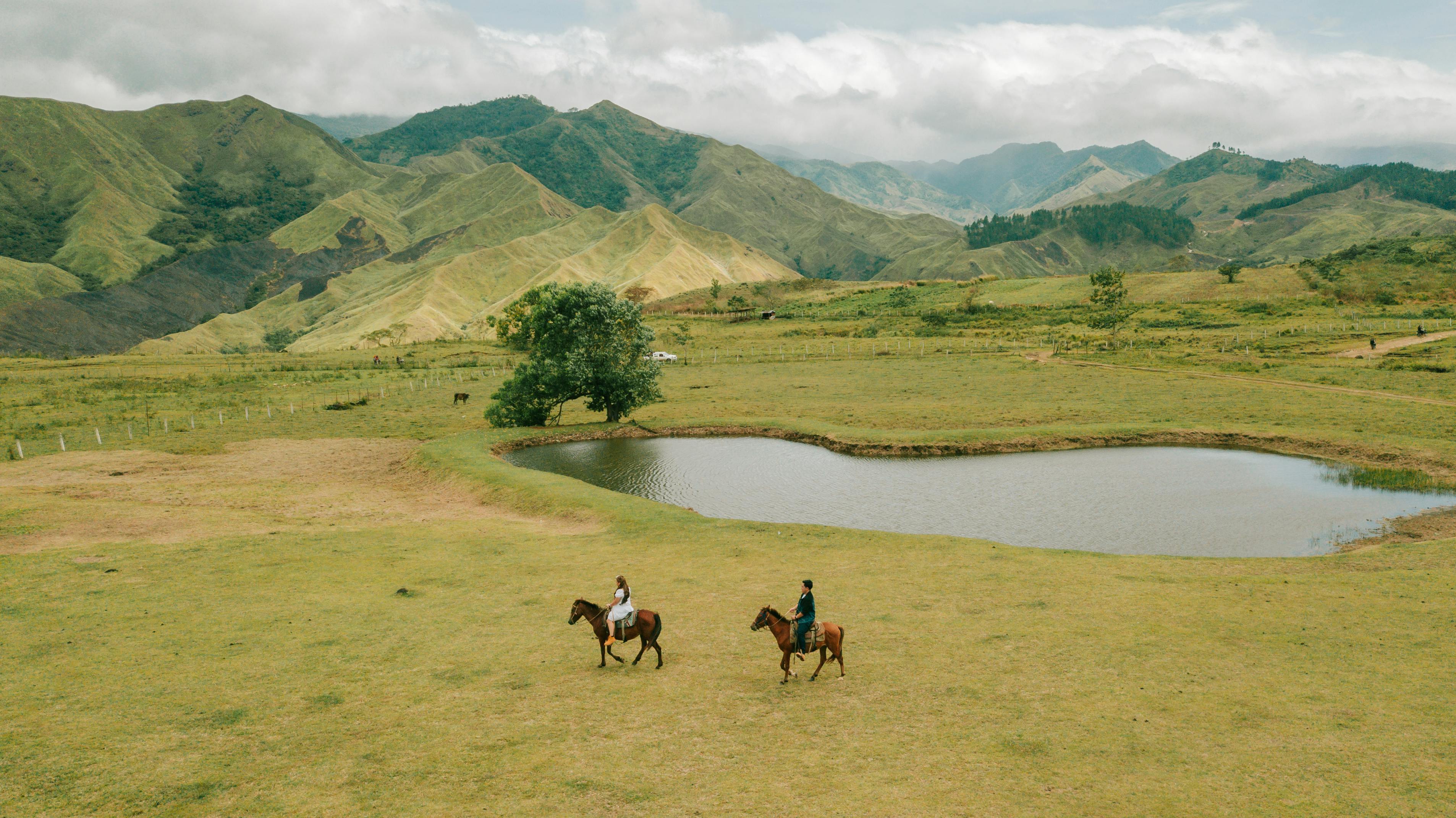 Aerial view of horseback riders in the lush mountains of Northern Mindanao, Philippines.