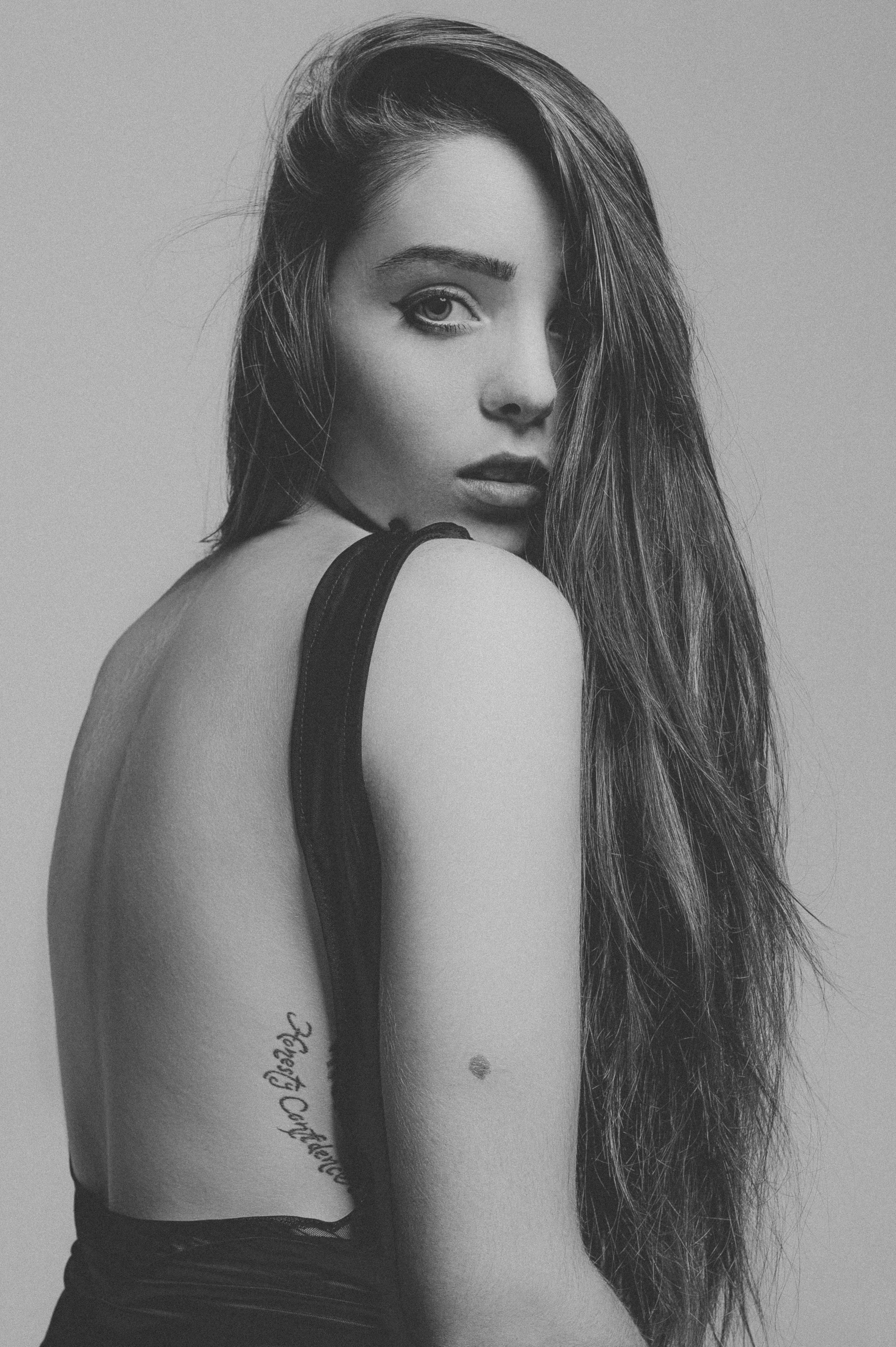 一幅引人注目的黑白肖像中，一位长发女子纹身明显，摆出优雅的姿势