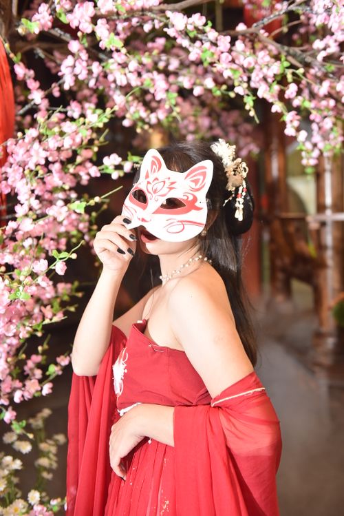 Free Woman in traditional attire with a fox mask amidst blooming cherry blossoms. Stock Photo