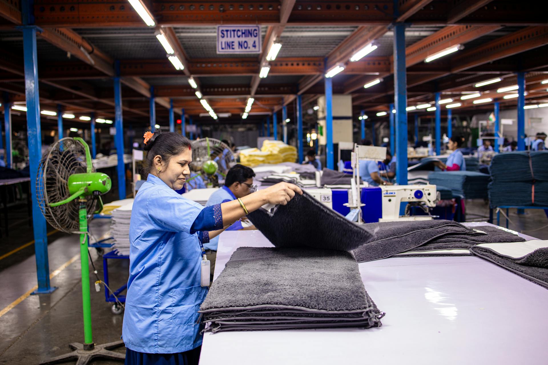 Indian woman working in a textile factory, folding fabric on a production line.