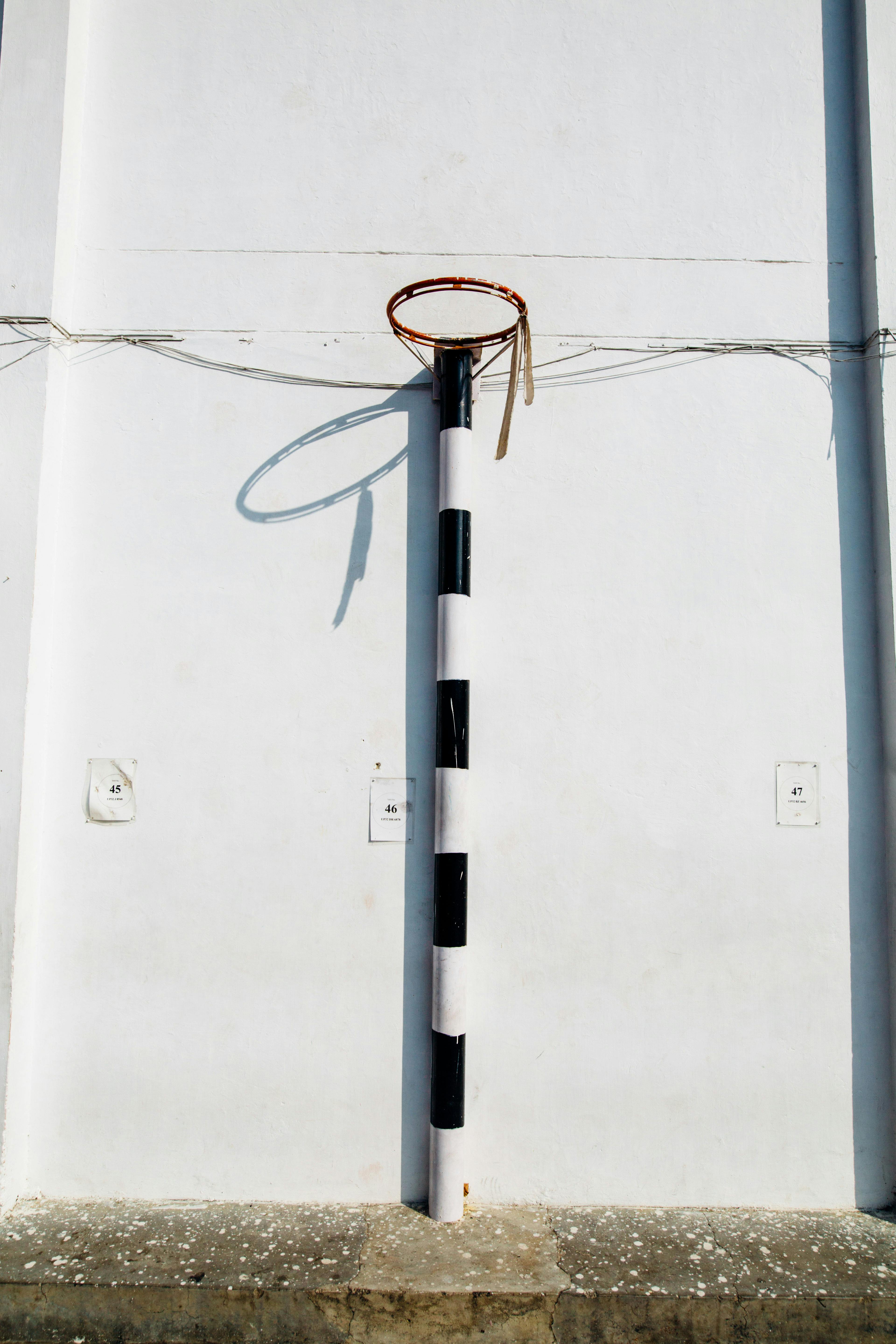 Simple basketball hoop against a white building wall in urban setting.