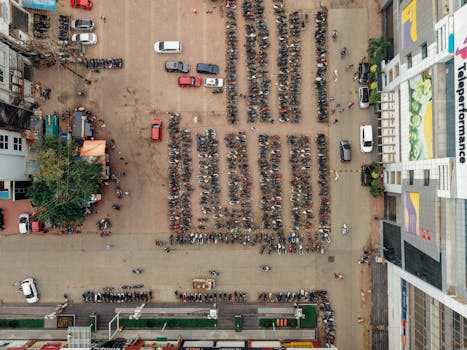 无人机拍摄了城市停车场里停放的摩托车和汽车，一片繁忙景象