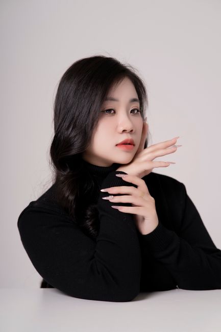 Stylish portrait of a woman in a black outfit with elegant pose against a neutral background.