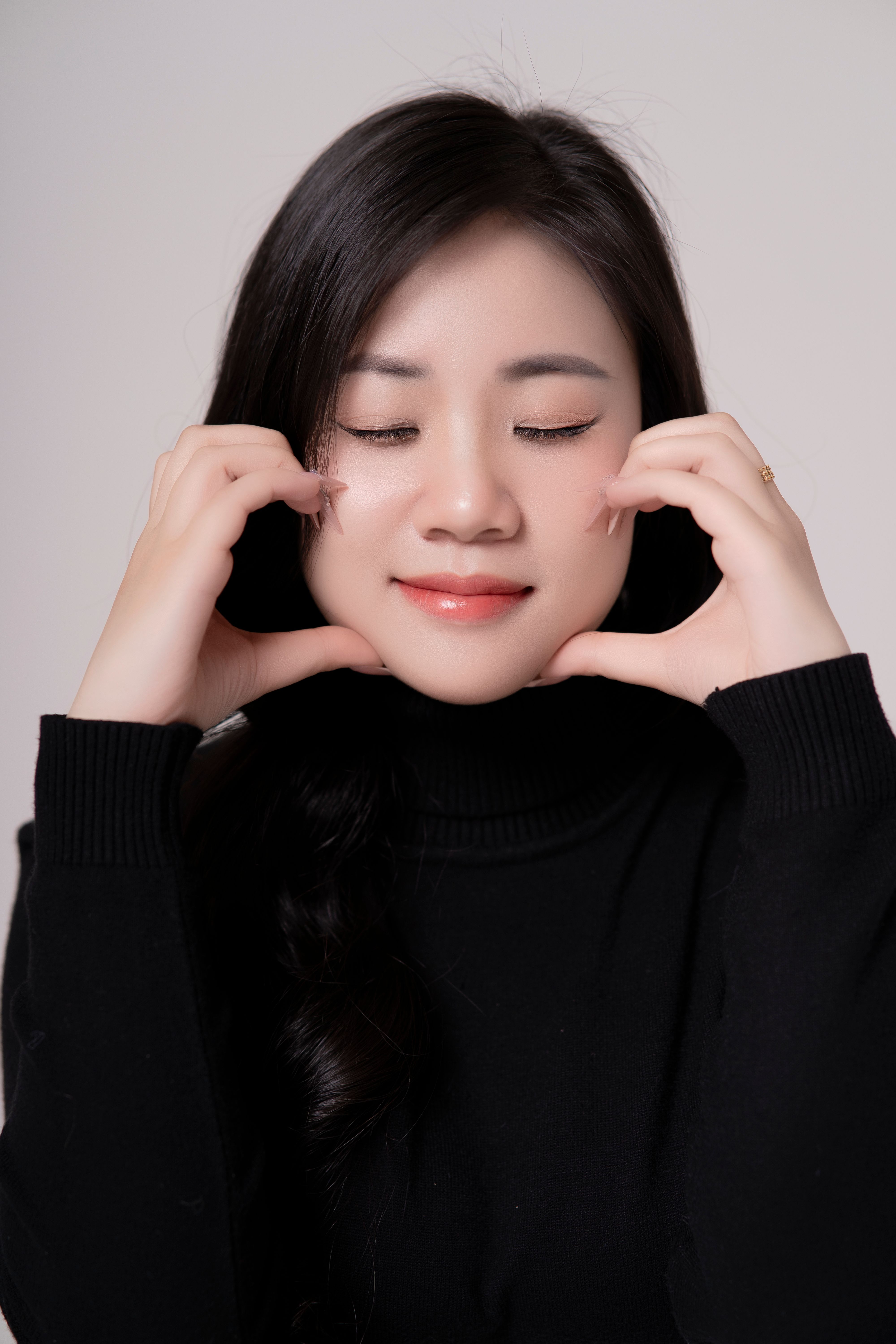 Gratuit Jeune femme en pull noir méditant avec une expression détendue et les yeux fermés. Photos