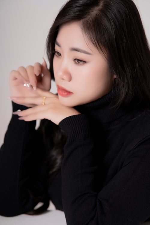 Gratuit Un portrait serein d'une jeune femme en pull noir, plongée dans ses pensées. Photos