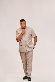 Portrait of an adult man in a beige suit with a thoughtful pose on a neutral background.