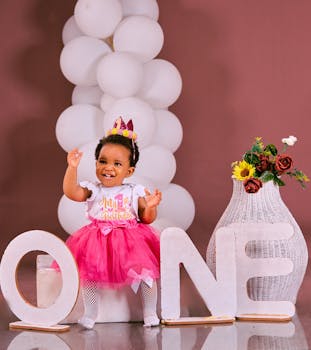Cute baby celebrating first birthday with balloons and decorations.