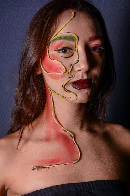 Free Creative face paint design with vibrant colors on a woman's face and neck displayed indoors. Stock Photo