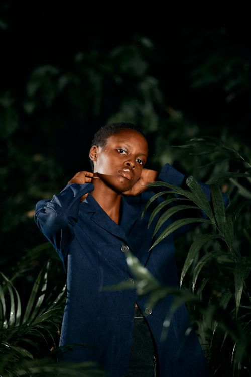 Free Striking portrait of a woman in a dark jungle setting, wearing a blue jacket. Stock Photo