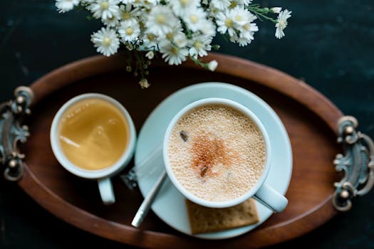 Aesthetic top-down view of a coffee cup, tea, and flowers on a vintage tray.