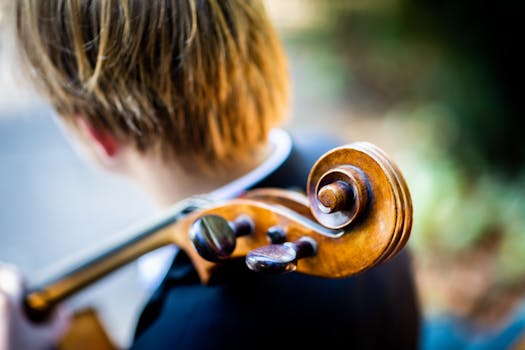 Close-up view of a violin's scroll with a musician playing outdoors.