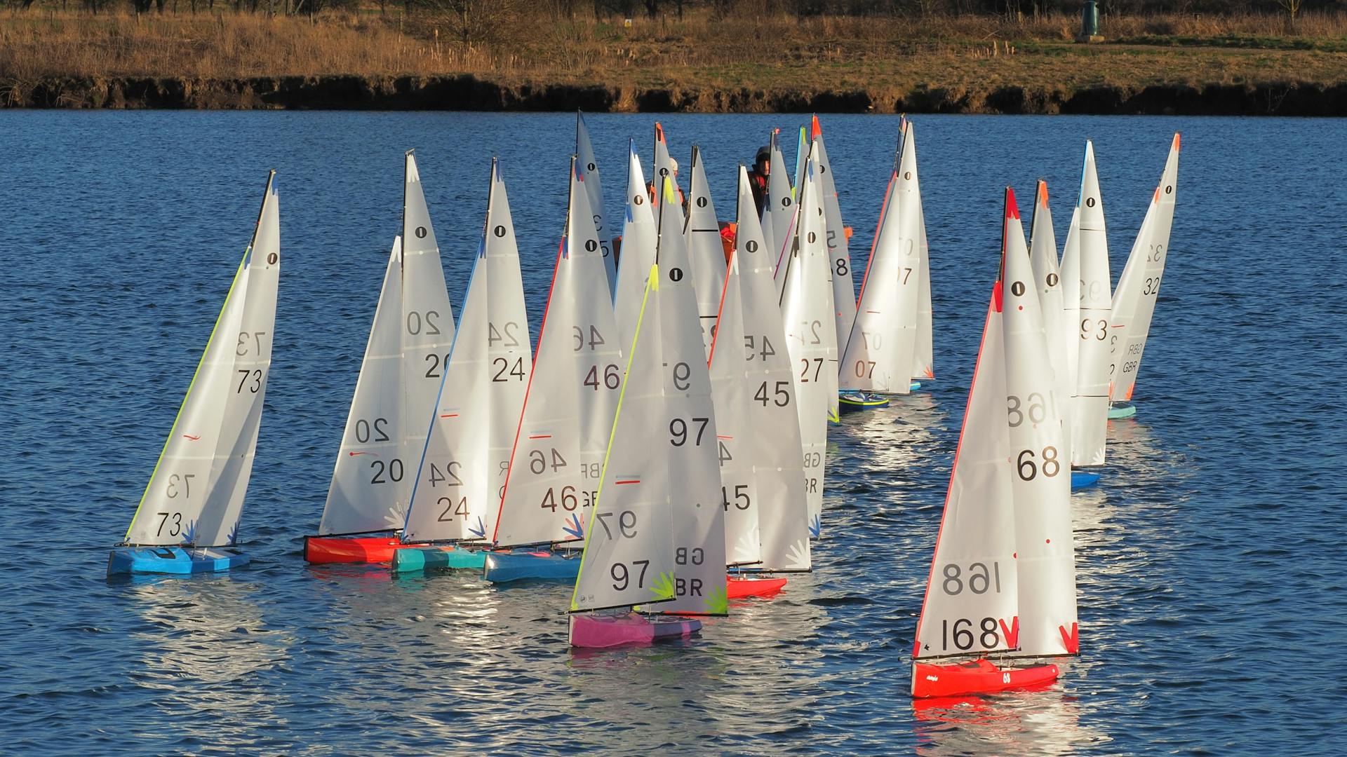 Colorful model yachts race on Wykeham Lake in England, showcasing radio sailing skills.