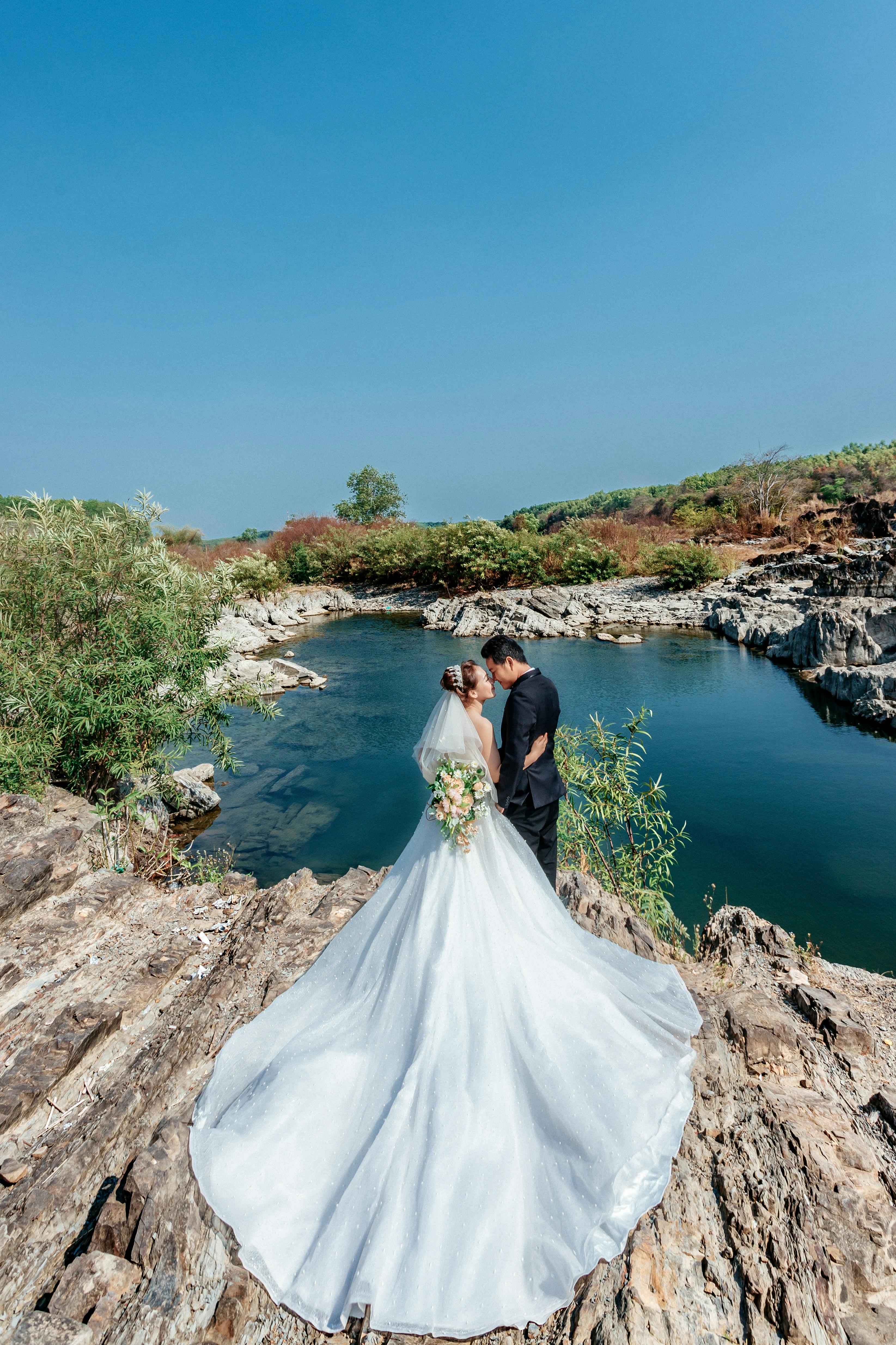 Bride and groom embrace by a picturesque lake in Dong Nai, Vietnam.