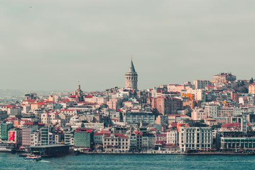 Free Aerial view of Istanbul's historic Galata Tower surrounded by buildings with the Bosphorus in the foreground. Stock Photo