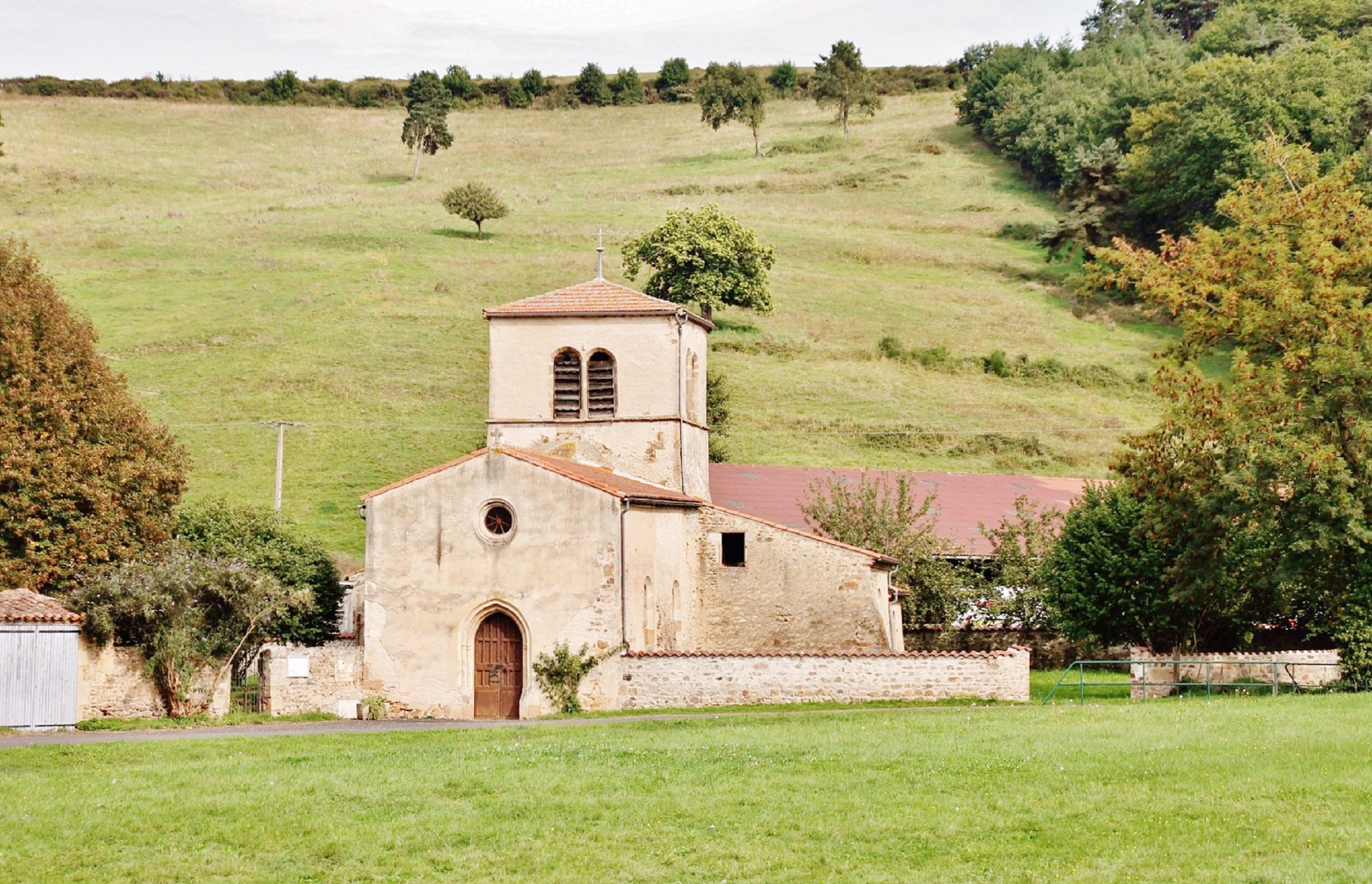 Charming old church set against a green hillside in Saint-Jean-en-Val, France.