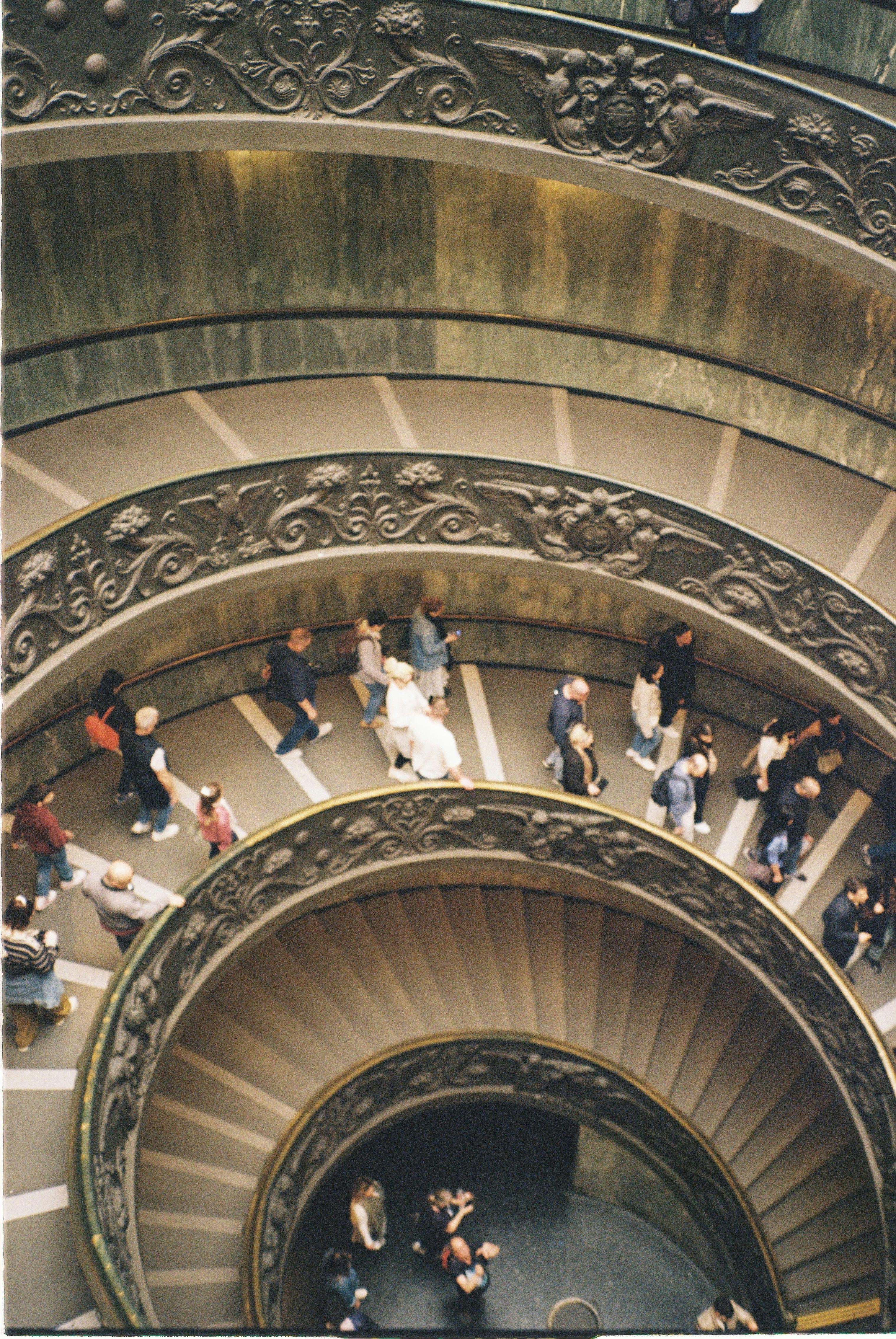 Iconic view of the Vatican Museums' spiral staircase with tourists ascending and descending.