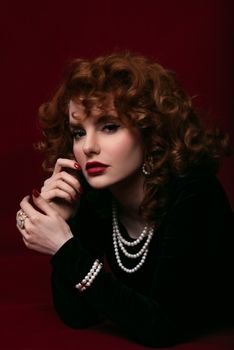 Elegant vintage-style portrait featuring a woman in pearls on a rich maroon backdrop.