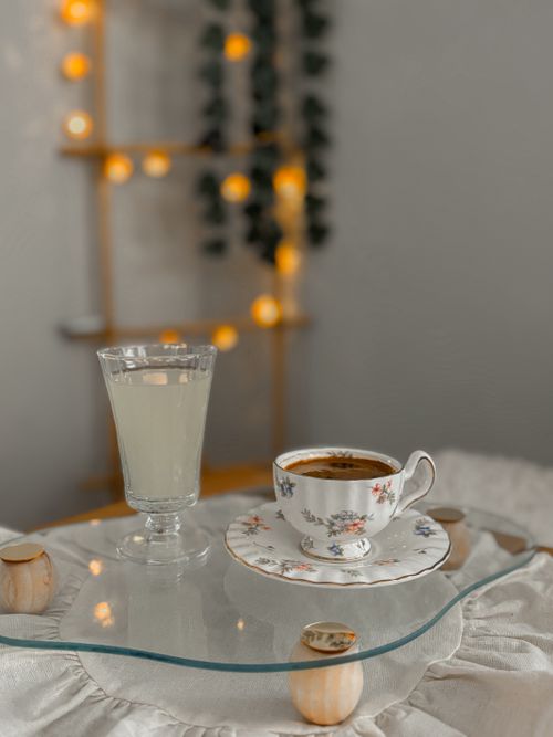 Free Comfortable indoor setting with floral cup of tea and lemonade on glass table. Stock Photo