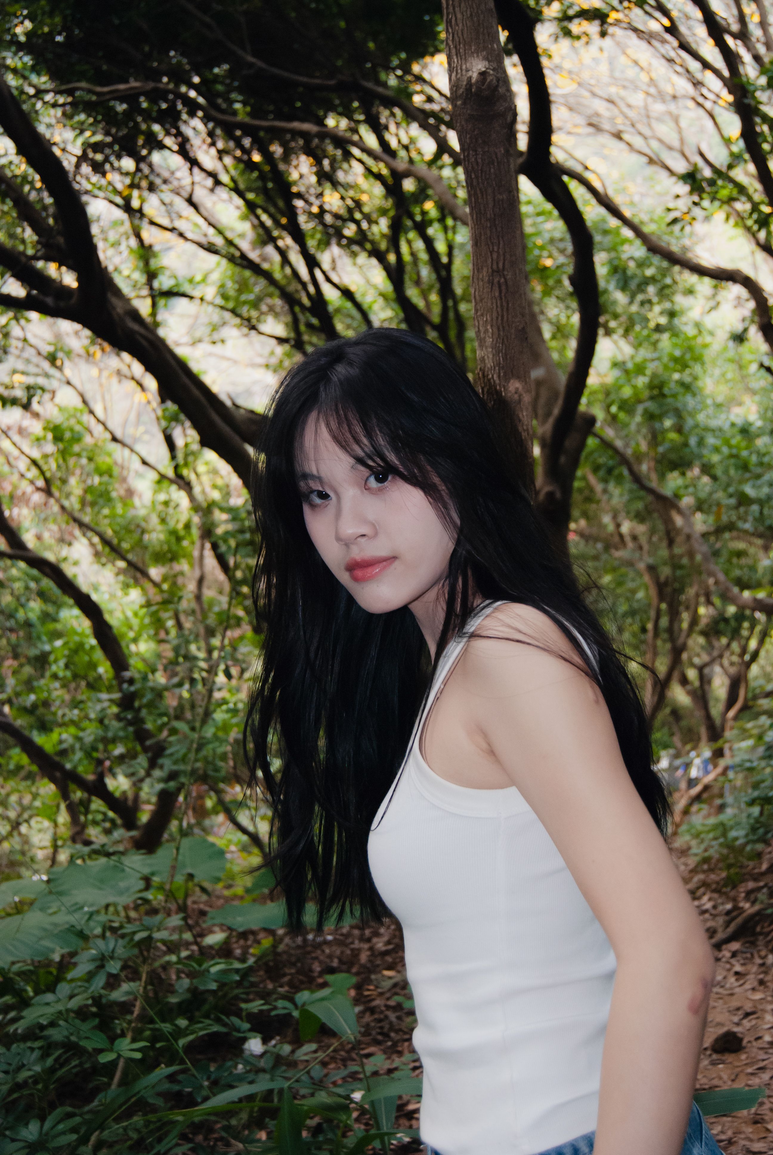 Portrait of a young woman in a forest, captured in natural light, exuding a serene connection with nature.