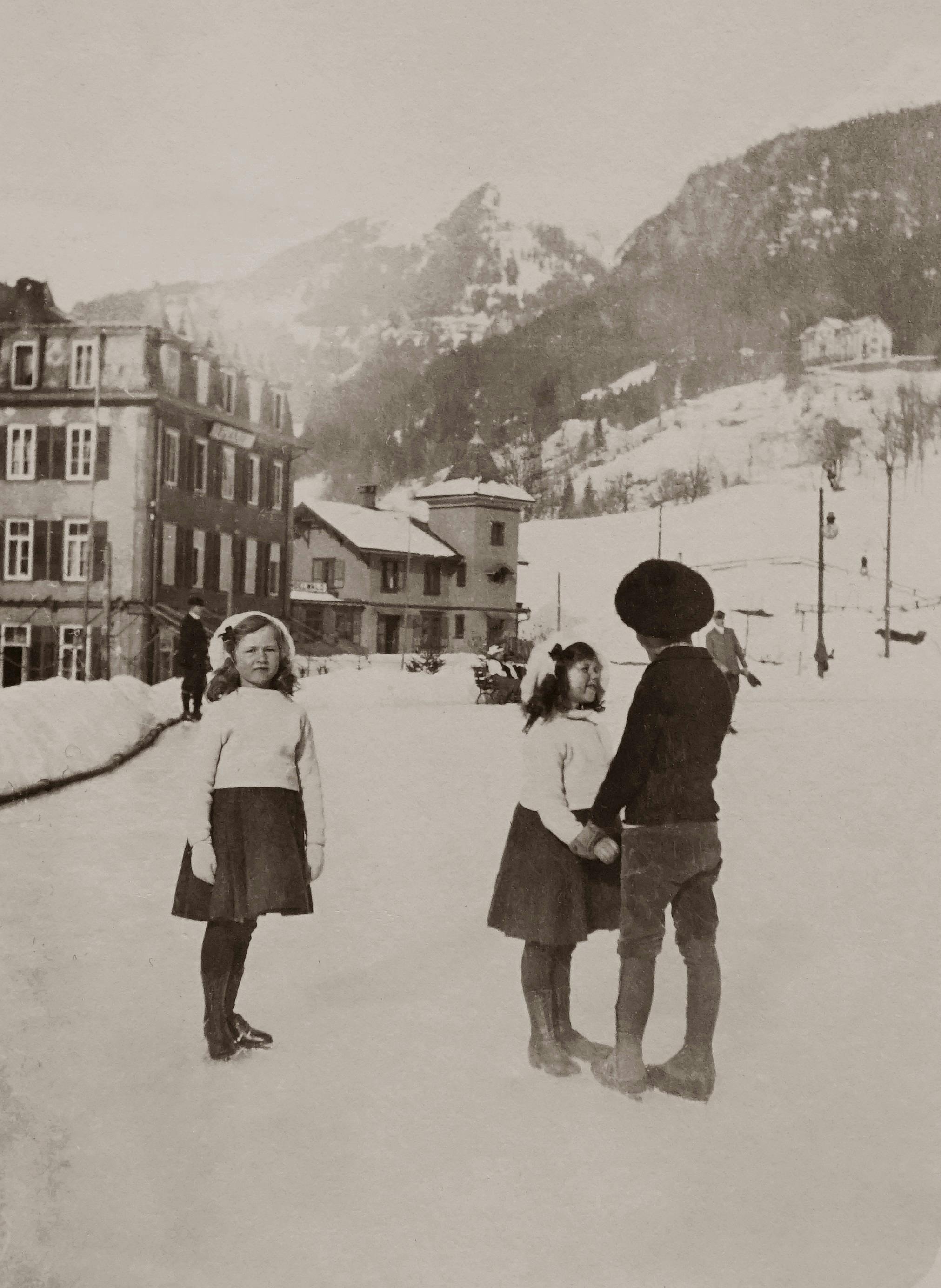 grayscale photo of two girls and a boy standing on snow covered road