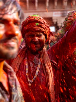 Men celebrating Holi with colorful powders, capturing the vibrant festival spirit in Nandgaon, India.