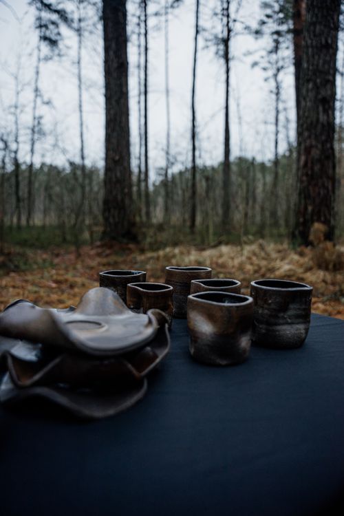 Free Handmade pottery cups set on table in tranquil forest ambiance, showcasing natural craftsmanship. Stock Photo
