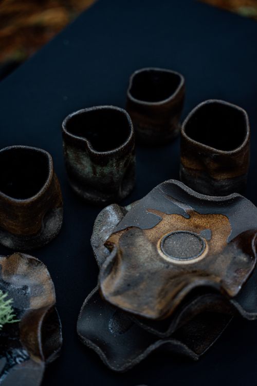 Free Artistic display of rustic handmade pottery set against a dark backdrop. Stock Photo
