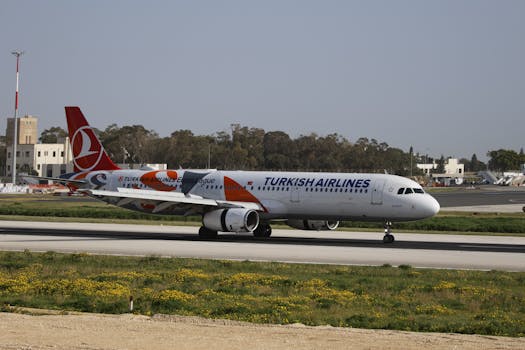 Turkish Airlines aircraft taxiing on a runway at daytime. Clear sky and airport structures visible.