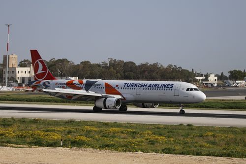Free Turkish Airlines aircraft taxiing on a runway at daytime. Clear sky and airport structures visible. Stock Photo