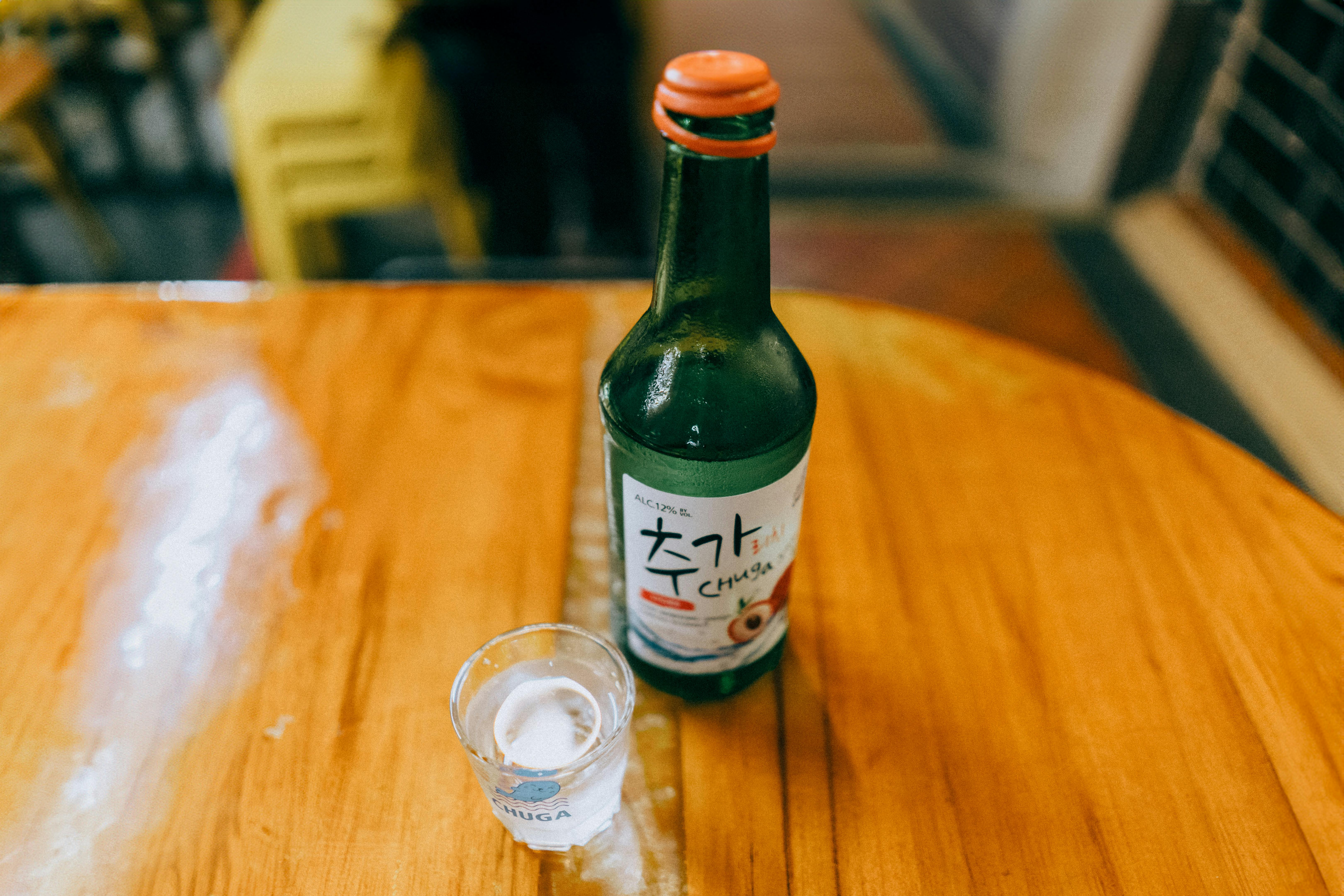 Free Korean soju bottle with shot glass on a wooden table in a cozy setting. Stock Photo