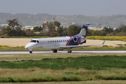 Private jet taxiing on a scenic runway with landscape background.