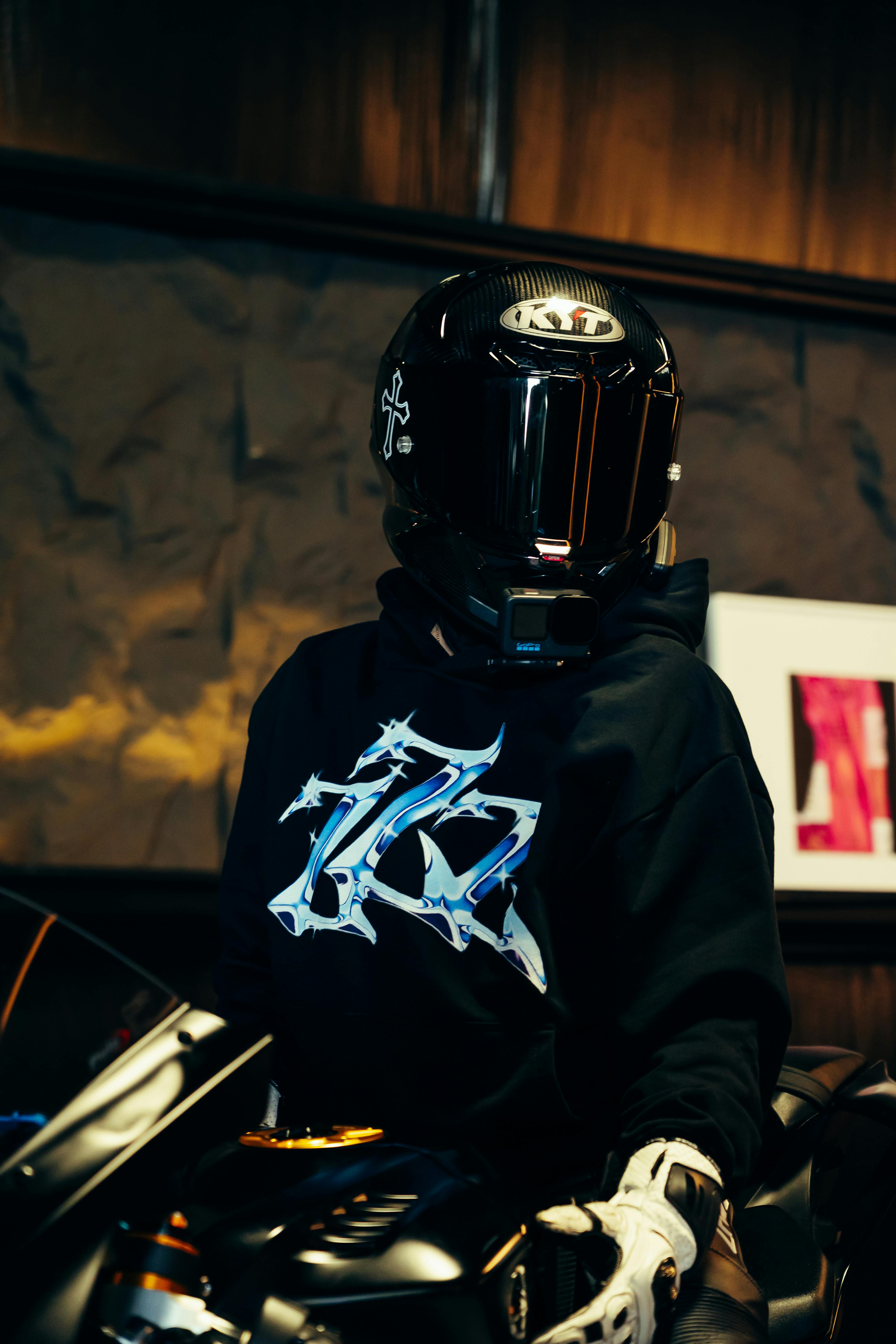 A person in a sleek motorcycle helmet posing indoors with a stylish background.