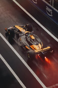Formula 1 car speeding on a wet track during a race, showcasing dynamic motion and sportsmanship.
