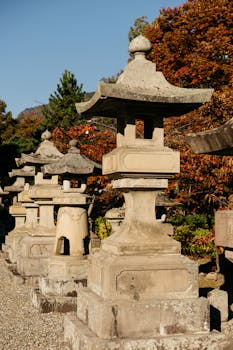 Row of traditional Japanese stone lanterns in a serene autumn setting.