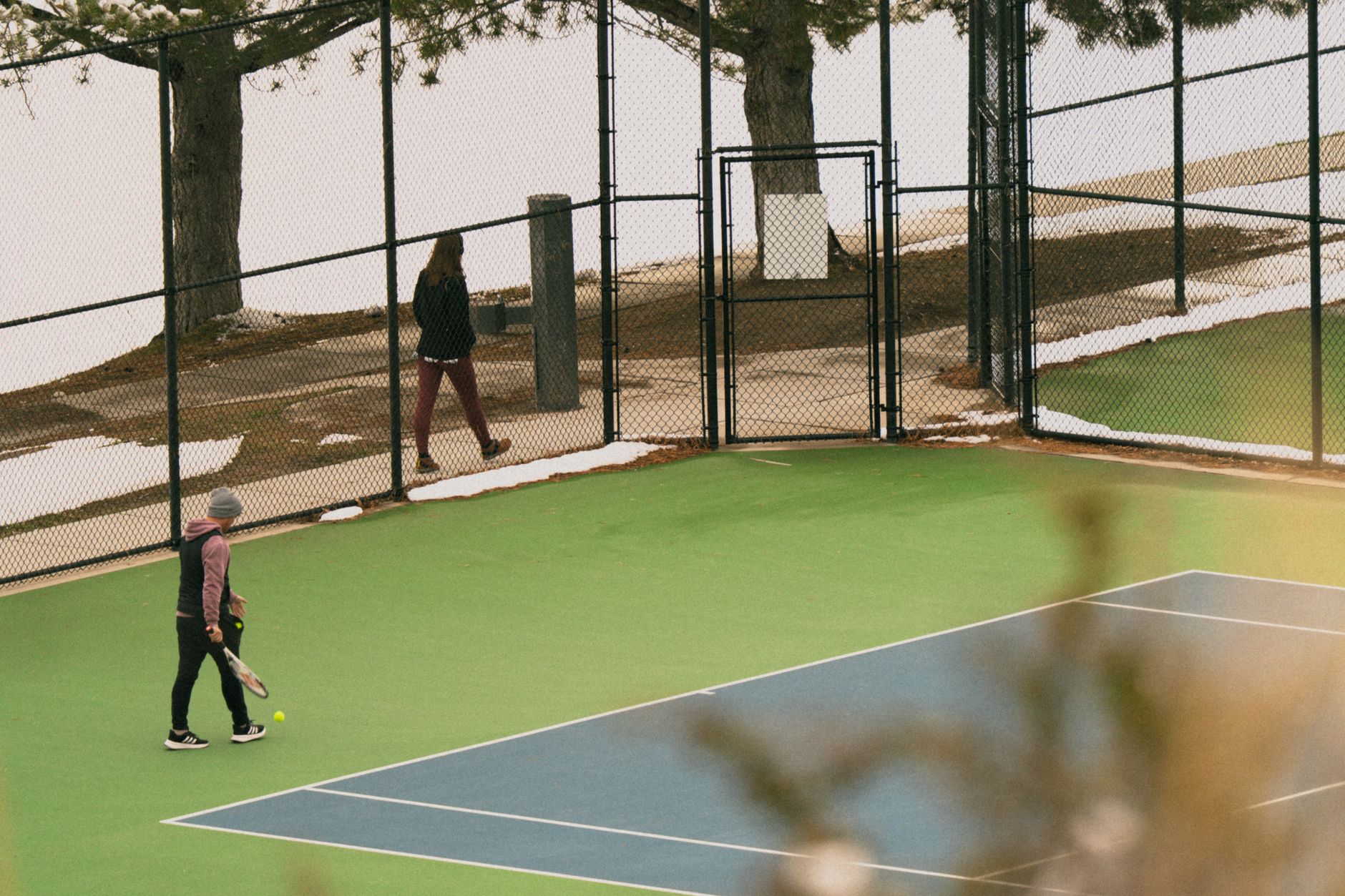 Tennis match in Salt Lake City amidst snow during spring, featuring players on a vibrant court.