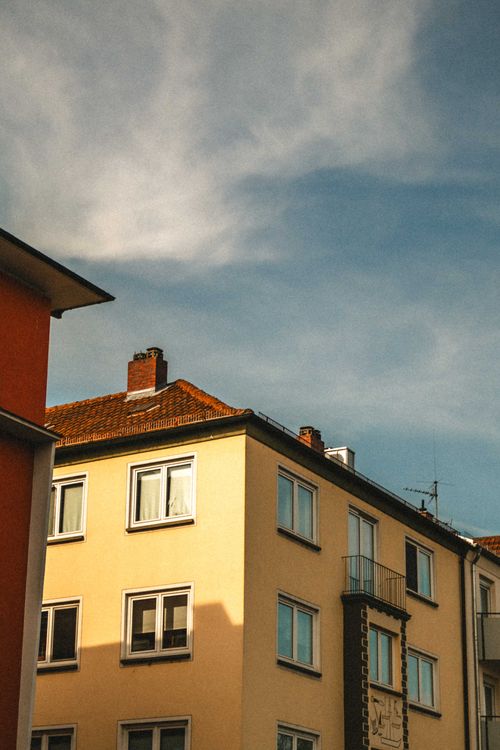 Free Capture of a charming urban building facade under a diffuse blue sky with clouds. Stock Photo
