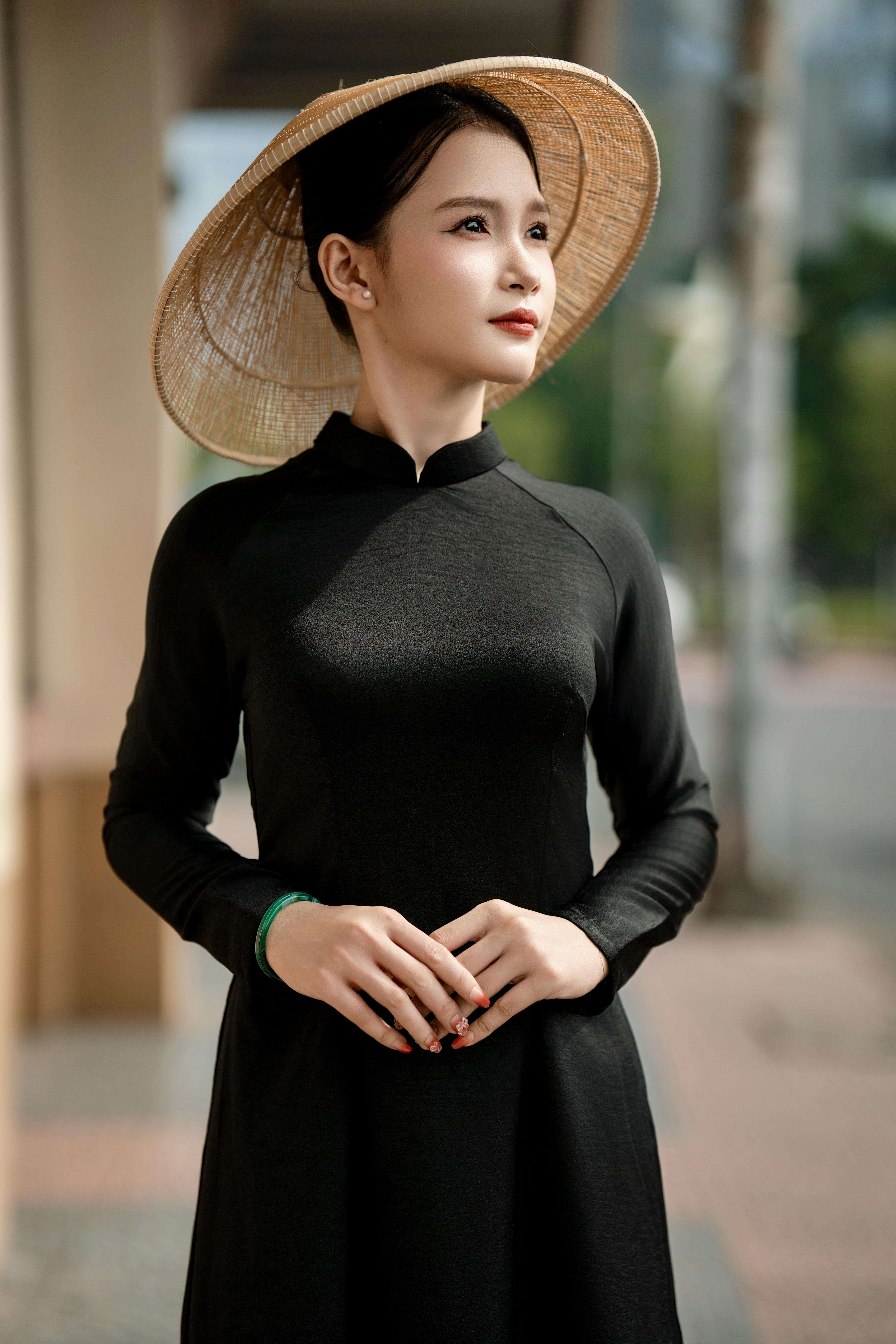 Young woman in traditional ao dai dress and straw hat outdoors.