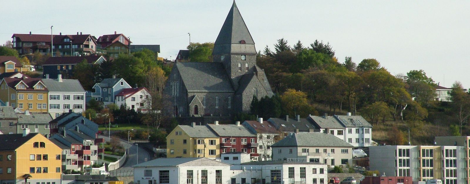 Picturesque view of a coastal town with a prominent stone church and colorful buildings.