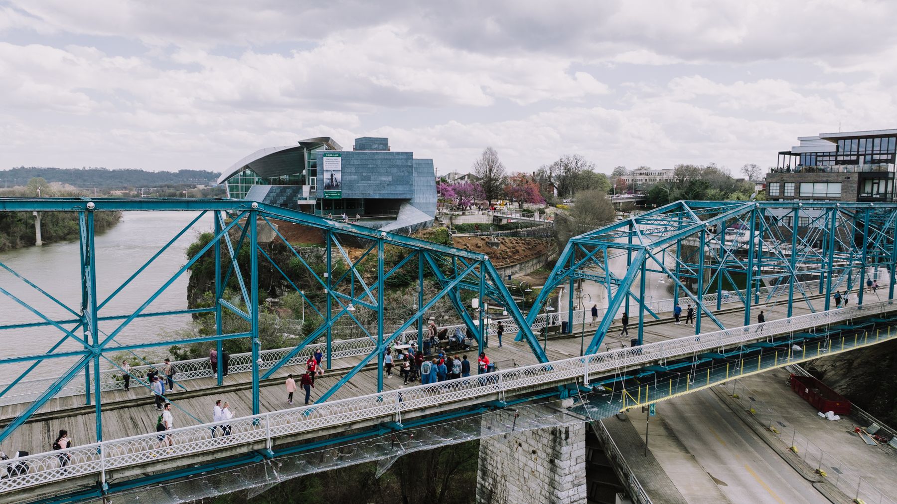 People walking across Walnut Street Bridge with the Hunter Museum visible beyond
