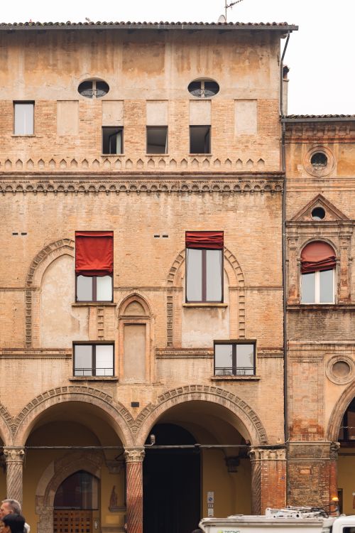 Free Detailed view of an ancient building facade in Bologna, Italy, showcasing arched windows and brickwork. Stock Photo