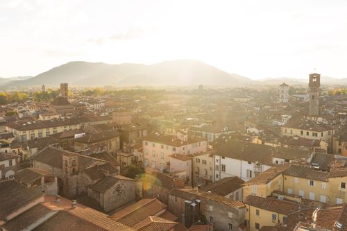 Free A picturesque aerial view of Lucca's historic rooftops at sunset, showcasing its architectural beauty. Stock Photo