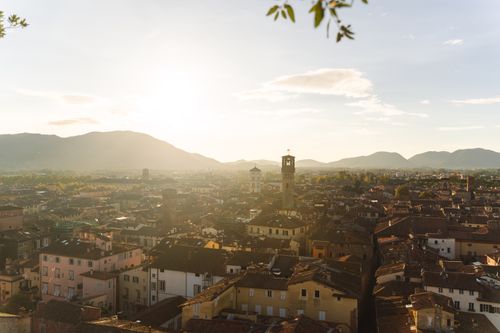 Free A scenic view of Lucca, Italy, during sunset, highlighting its historic architecture and mountainous backdrop. Stock Photo