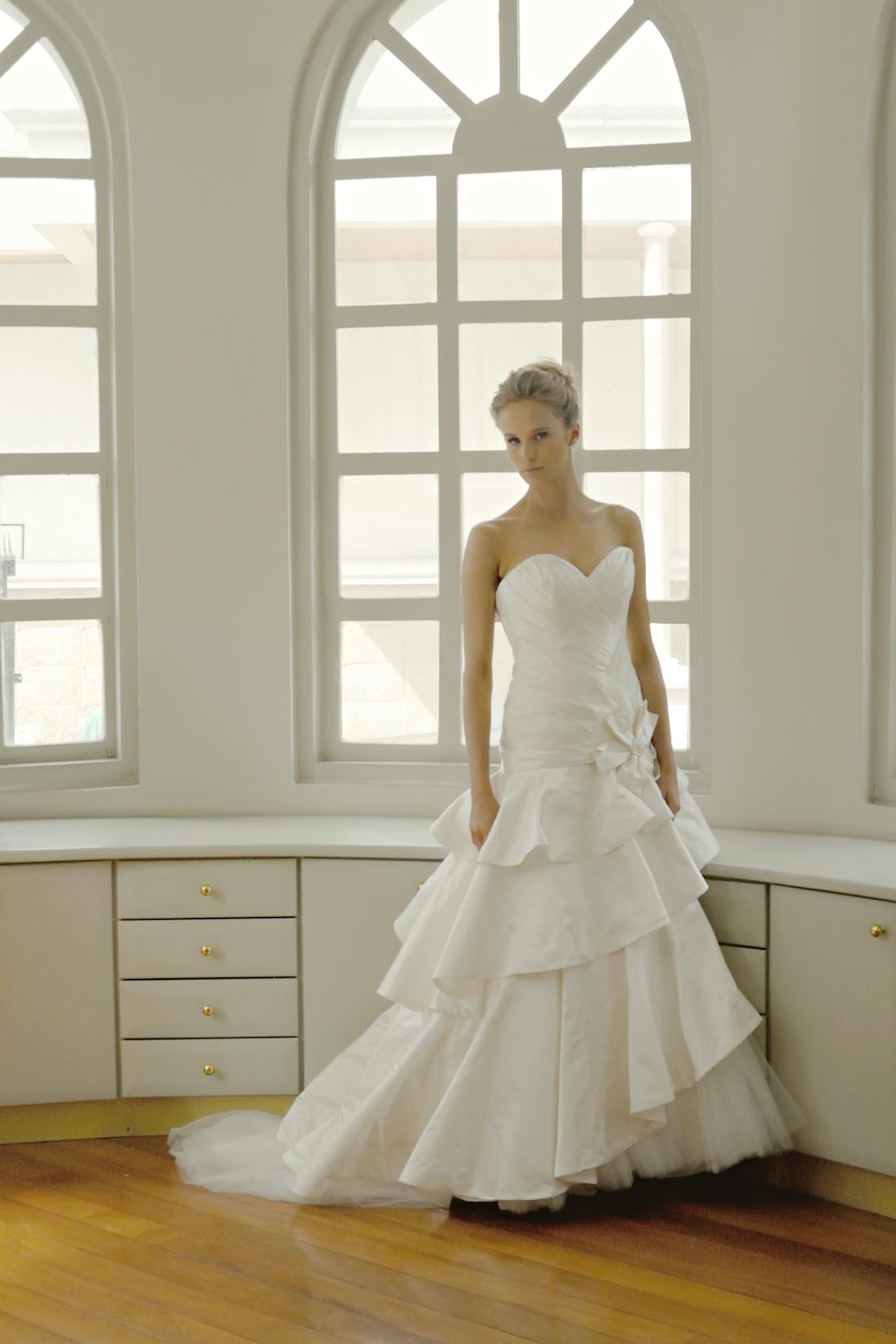 Layered white gown with voluminous skirt details under soft lighting