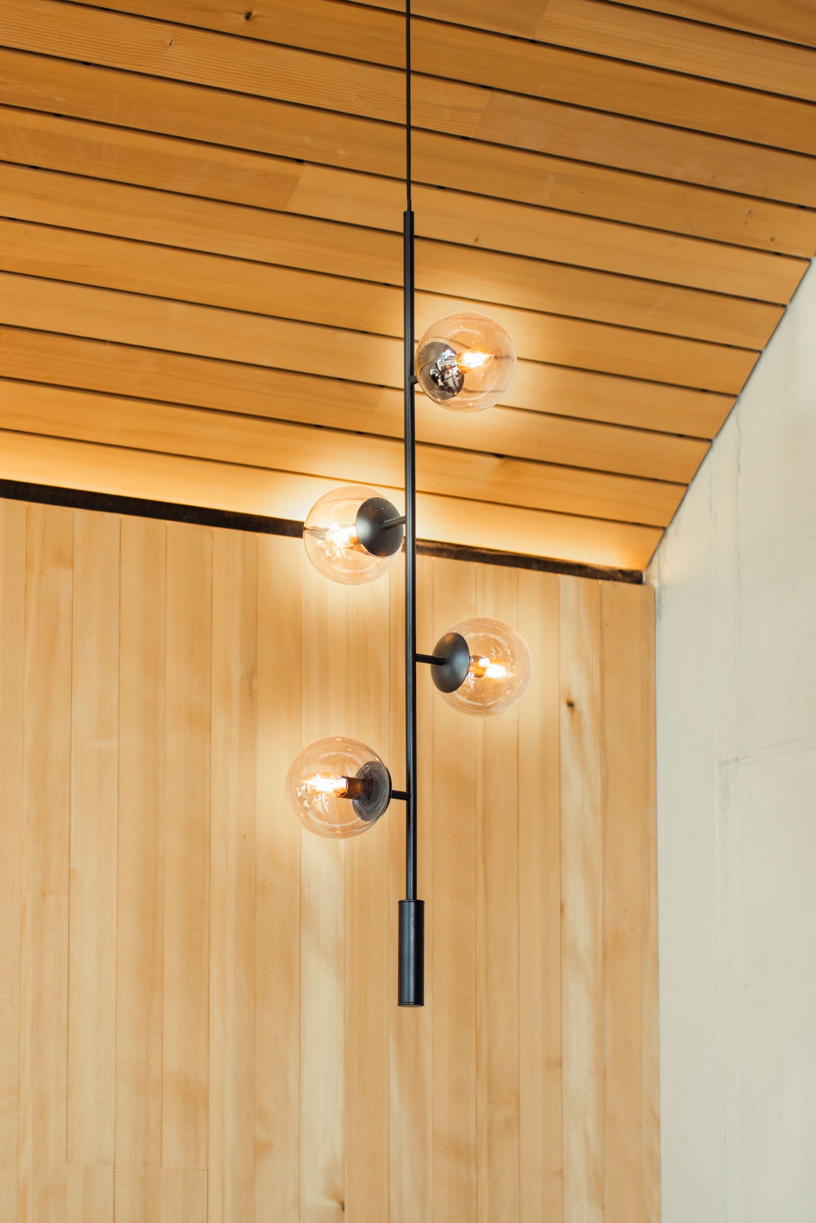 A single pendant light against a timber-slat ceiling